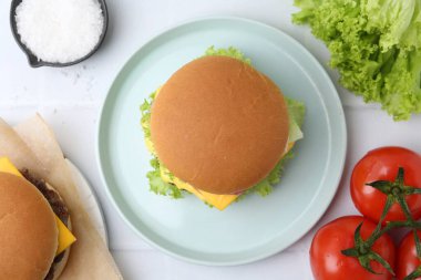 Lezzetli çizburger ve malzemeler beyaz masada, düz yerde.