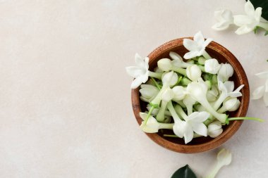 Üzerinde yasemin çiçekleri olan bir kase bej masa, düz. Metin için boşluk