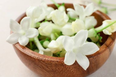 Bej masanın üzerinde yasemin çiçekleri olan kase, yakın plan.