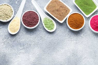 Gri desenli masa üzerinde farklı süper yiyecek tozları, düz yatak. Metin için boşluk