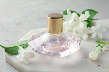 Parfüm ve yasemin çiçekleri açık gri masada, yakın plan