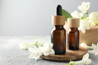 Gri masa üzerinde gerekli yağ ve yasemin çiçekleri, yakın plan. Metin için boşluk