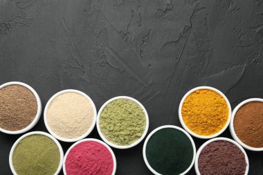 Koyu dokulu masada, düz yerde, kaselerde farklı süper yiyecek tozları var. Metin için boşluk