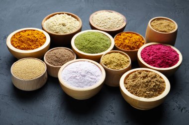 Koyu dokulu masadaki kâselerde farklı süper yiyecek tozları.