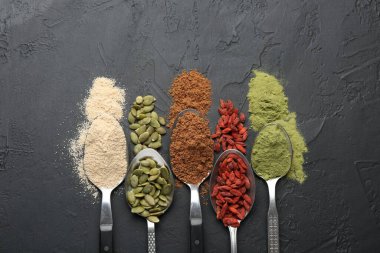 Siyah masadaki kaşıklardaki farklı süper yiyecekler.