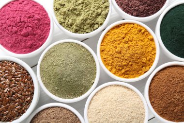 Beyaz ahşap masadaki kaselerdeki farklı süper yiyecek tozları.