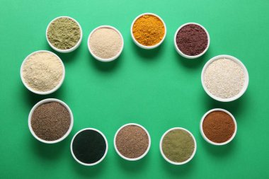 Yeşil arka plandaki kaselerde farklı süper yiyecek tozlarının çerçevesi düz. Metin için boşluk