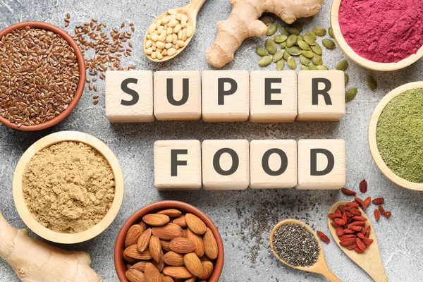 Farklı süper yiyecekler ve gri desenli masa üzerindeki küplerden yapılmış kelimeler.