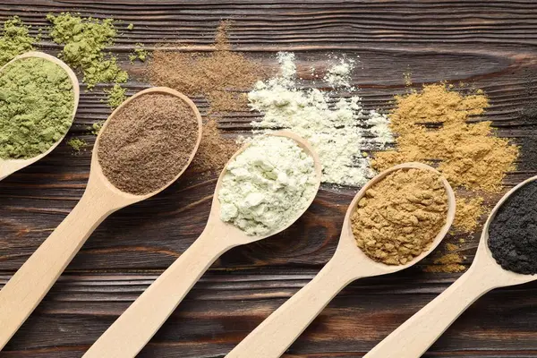 Farklı süper yiyecek tozları ve kaşıklar ahşap masada, düz yatıyordu.