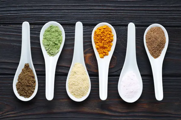 Tahta masadaki kaşıklarda farklı süper yiyecek tozları.