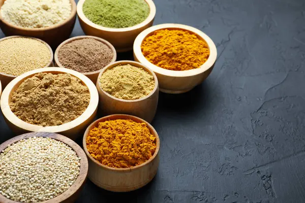 Koyu dokulu masadaki kaselerde farklı süper yiyecek tozları, yakın plan. Metin için boşluk