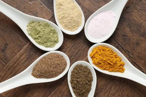 Tahta masadaki kaşıklarda farklı süper yiyecek tozları.