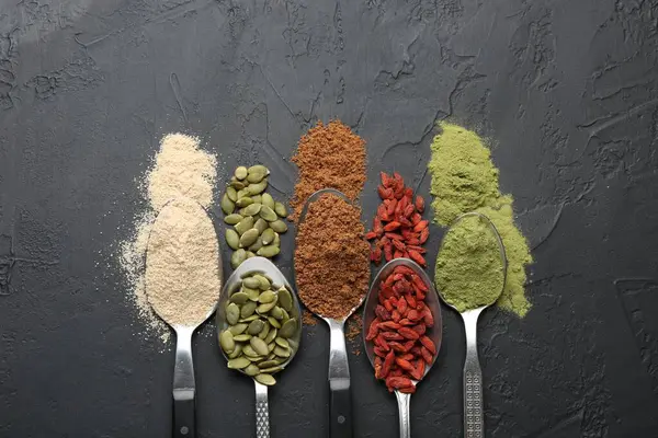 Siyah masadaki kaşıklardaki farklı süper yiyecekler.