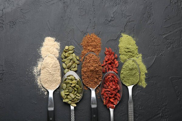 Различные суперпарфюмерии в ложках на черном столе, плоская укладка