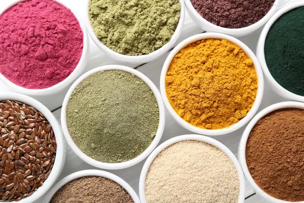 Beyaz ahşap masadaki kaselerdeki farklı süper yiyecek tozları.