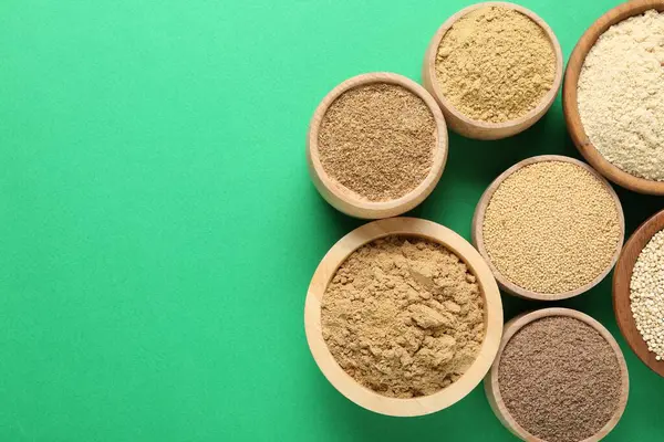 Yeşil arka planda kaselerde farklı süper yiyecek tozları var. Metin için boşluk