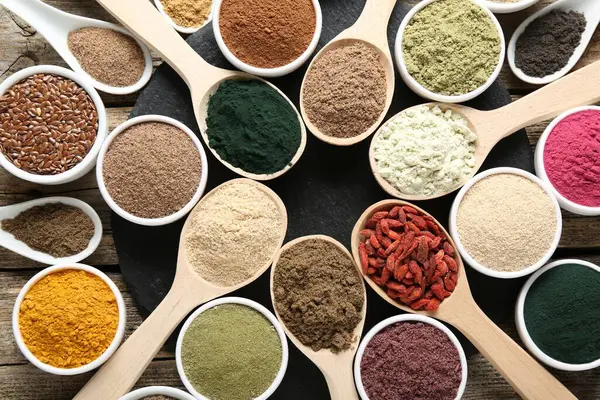 Tahta masada, düz yerde, kaşıklardaki ve kaselerdeki farklı süper yiyecekler.