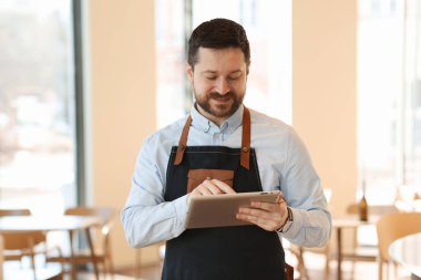 Kafesinde tabletle çalışan yakışıklı bir işletme sahibi.