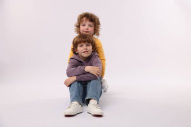 Beyaz arka planda poz veren şirin küçük kardeşler.