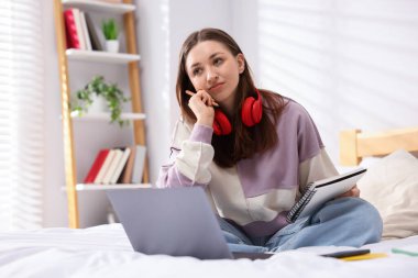 Genç kız evde laptopun yanında ödev yapıyor.