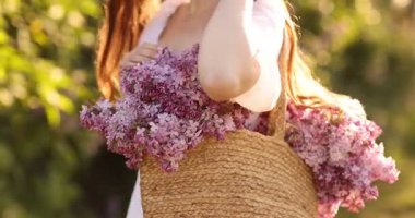 Güneşli bir sabahta, açık havada bir çanta leylak çiçekli kadın, yakın plan.