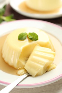 Karamel soslu lezzetli puding ve beyaz masada servis edilen nane şekeri.