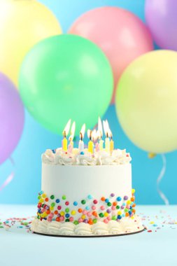 Nefis bento keki, üzerine şeker serpiştirilmiş ve mavi arka planda yanan mumlar.