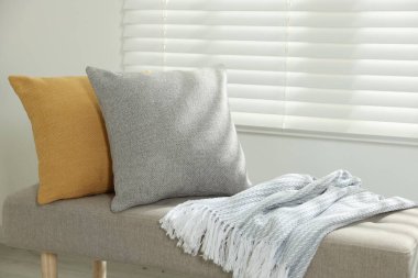 Odadaki kanepede yumuşak dekoratif yastıklar ve battaniye.