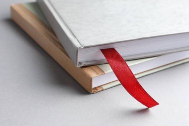 Kırmızı kurdele yer imi ve açık gri masada renkli bir kitap, yakın plan.