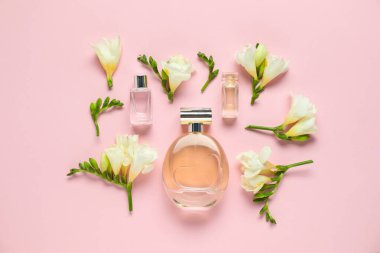 Parfüm şişeleri ve pembe arka planda güzel çiçekler.