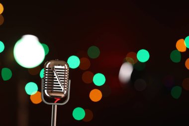Karanlık arka planda bulanık ışıkları olan klasik mikrofon, mesaj için yer. Müzik ekipmanları