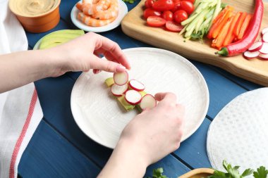 Mavi ahşap masada nefis börek yapan bir kadın.