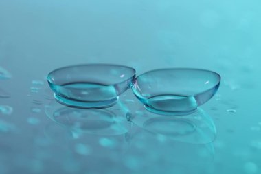 Renkli ayna yüzeyine kontak lens ve su damlaları, yakın plan.