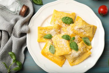 Açık mavi ahşap masada servis edilen peynirli ve fesleğenli nefis ravioli.