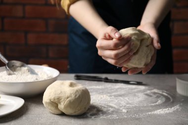 Açık gri masada hamur yoğuran kadın, yakın plan.