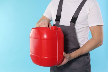 Açık mavi arka planda plastik kutu tutan adam, yakın plan. Metin için boşluk