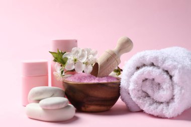 Kozmetik ürünleriyle spa kompozisyonu, çakıl taşları ve pembe arka planda güzel çiçekler, yakın plan.