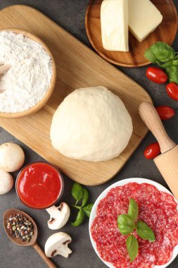 Pizza yapıyorum. Gri desenli masa üzerindeki farklı malzemeler.