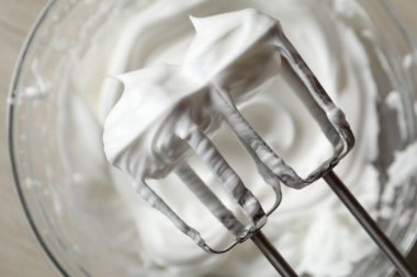 Kasenin üzerinde çırpılmış krema ve çırpılmış çırpılmış çırpmalı el çırpıcısı, üst manzara.