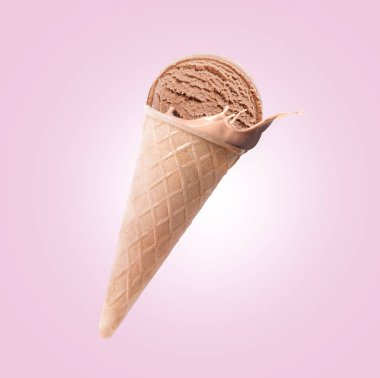 Waffle külahında çikolatalı dondurma ve pembe arka planda biraz süt.