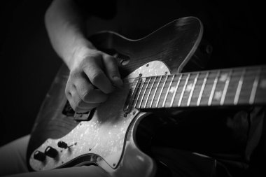 Karanlıkta gitar çalan adam, yakın plan. Siyah ve beyaz etkisi
