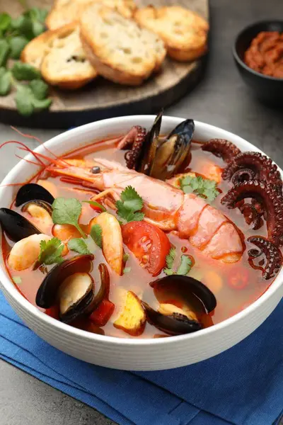 Lezzetli deniz ürünleri çorbası gri masada, yakın plan.