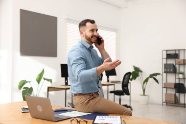 Ofiste çalışan bir adam telefonda konuşuyor.