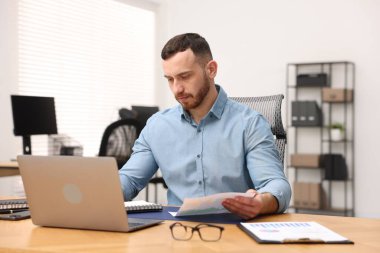 Ofiste masa başında çalışan yakışıklı adam.