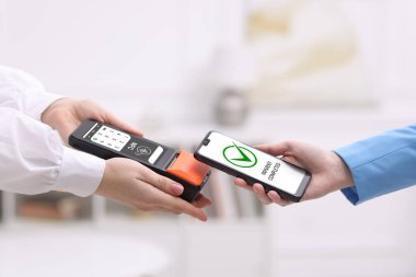 NFC sistemli ödeme terminali. Kapalı mekanda servis için cep telefonu kullanan bir müşteri.