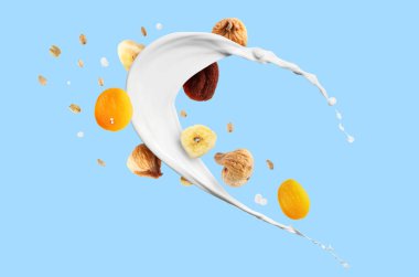 Süt sıçraması, yulaf ezmesi ve açık mavi arka planda kurutulmuş meyve. Sağlıklı kahvaltı.