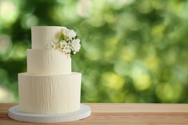 Dışarıdaki ahşap masada çiçeklerle süslenmiş güzel bir düğün pastası. Metin için boşluk