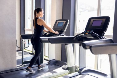 Spor salonunda koşu bandında antrenman yapan atletik kadın.