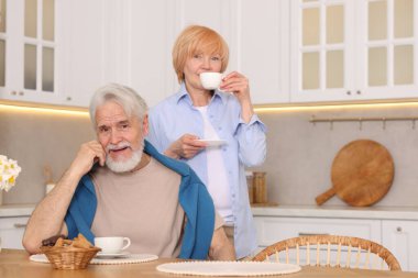 Mutfaktaki ahşap masada birlikte kahvaltı eden sevimli yaşlı çift.