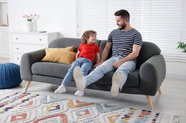 Mutlu baba ve oğlu evdeki kanepede birlikte vakit geçiriyorlar.